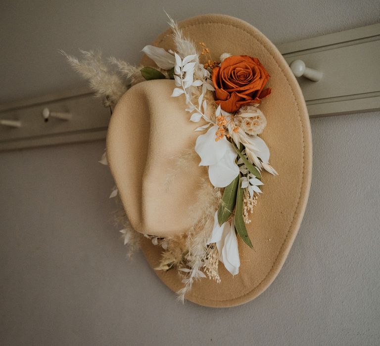 Cream coloured fedora with dried flower and burnt orange rose decorations around the rim, hand made by the bride