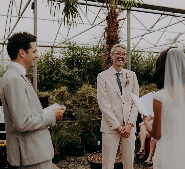 Groom laughing while the Bride reads from vow book during ceremony