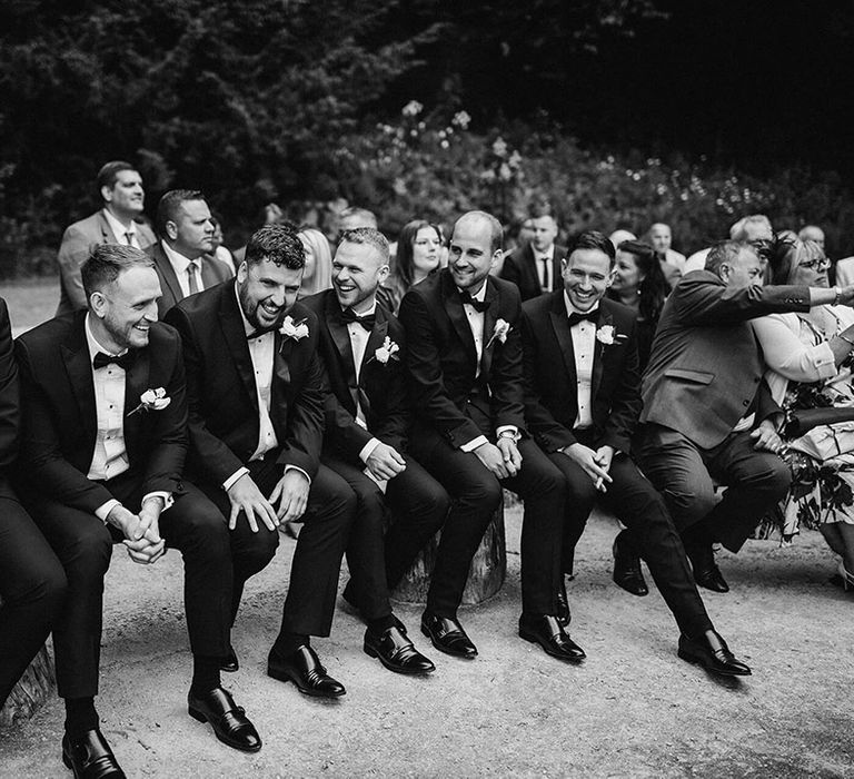 The groomsmen in black tie all sit together on the front row for the wedding ceremony at The Orangery 