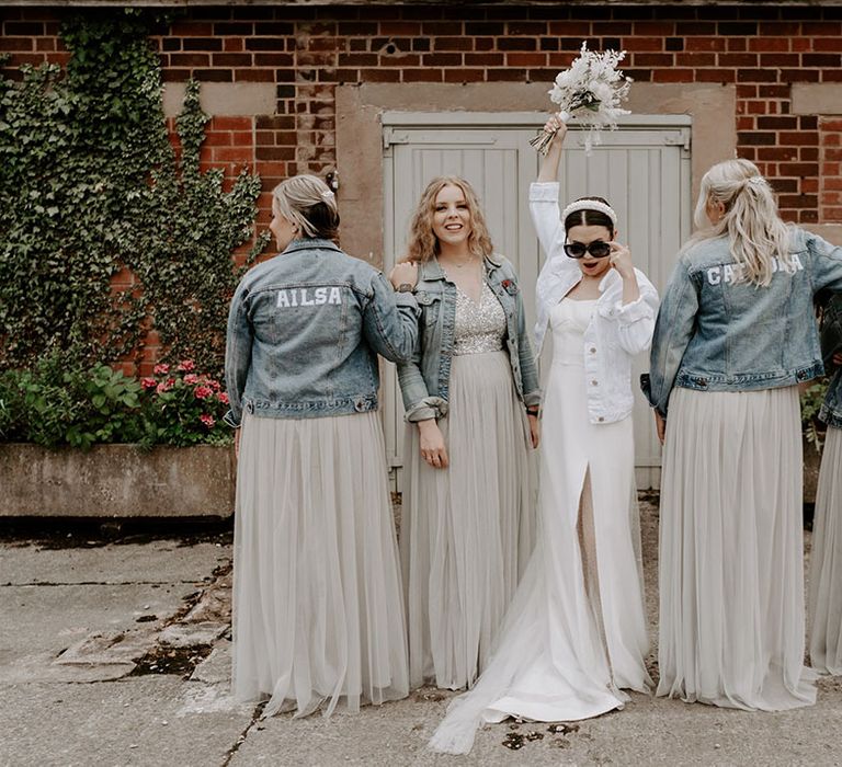 Bridesmaids wear customised light blue denim jackets with the bride in a white denim jacket, pearl headband and black sunglasses 