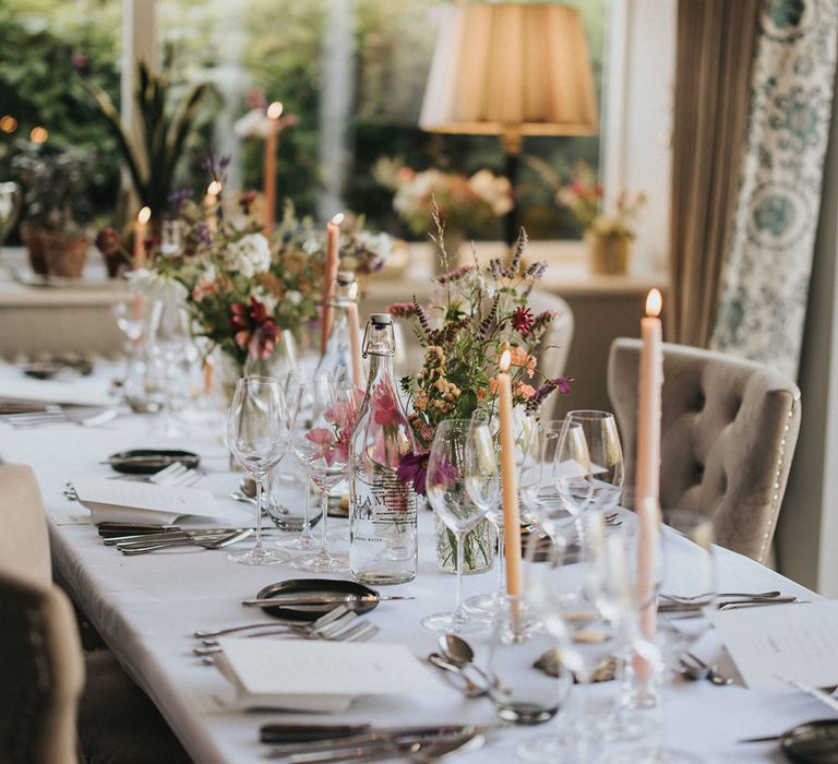 Cream taper candles decorating the wedding tablescape with rustic wedding flowers and wildflowers with traditional simple place settings 