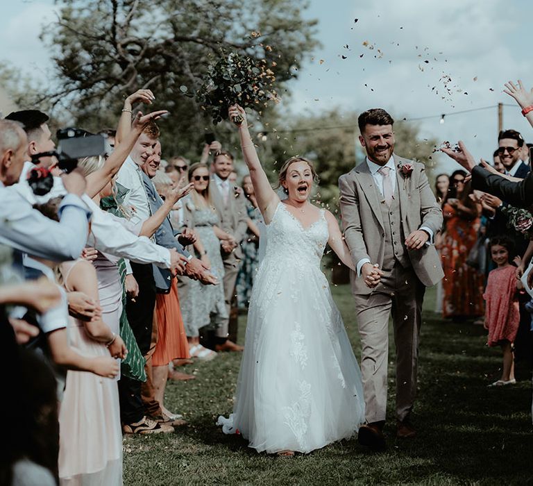 Bride & groom walk through colourful confetti exit after outdoor wedding ceremony at The Apple Orchard 