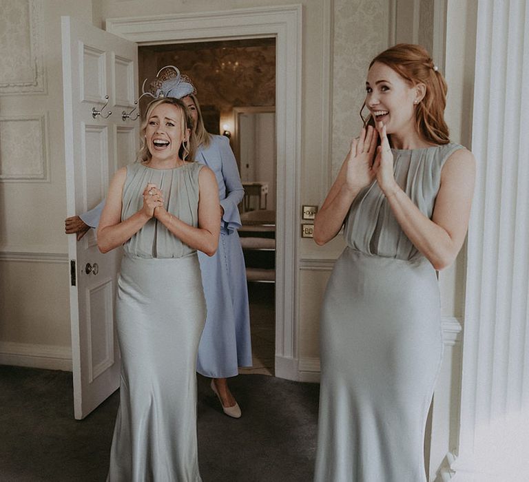 Bridesmaids in sage green bridesmaid dresses see bride for the first time on the morning of her wedding day