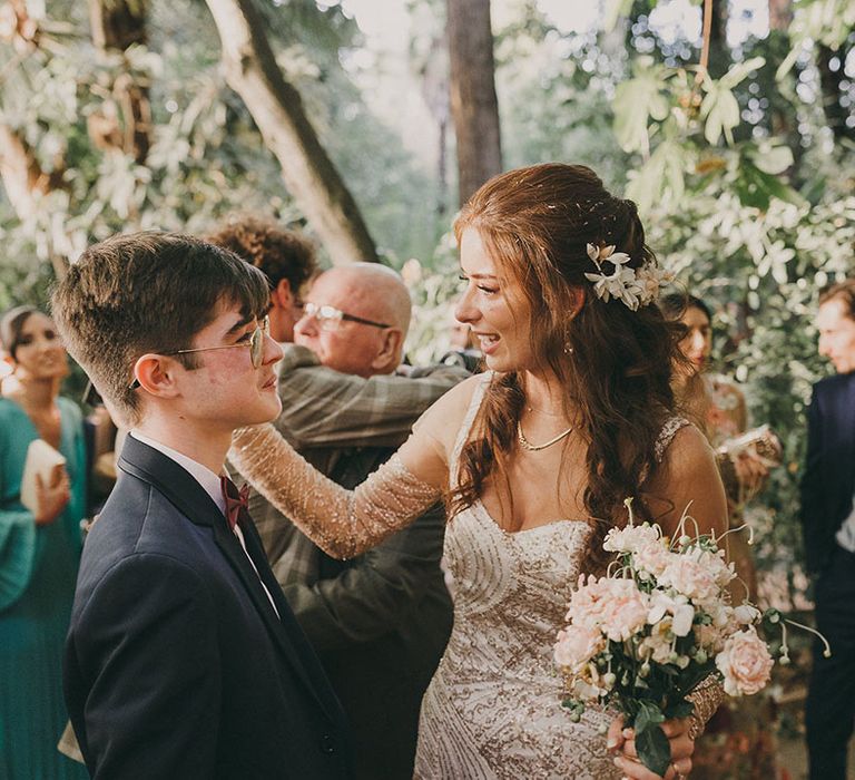 bride in a gold sparkly wedding dress with sleeves holding a pink flower bouquet 