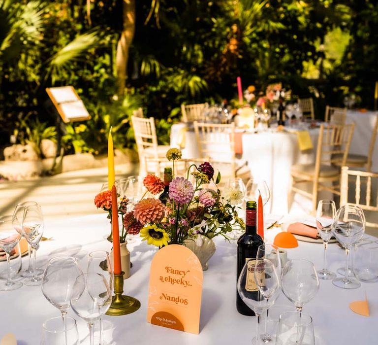 Orange wedding table sign names based on fast food restaurants with bright candles and bud vases to decorate the table centrepieces 