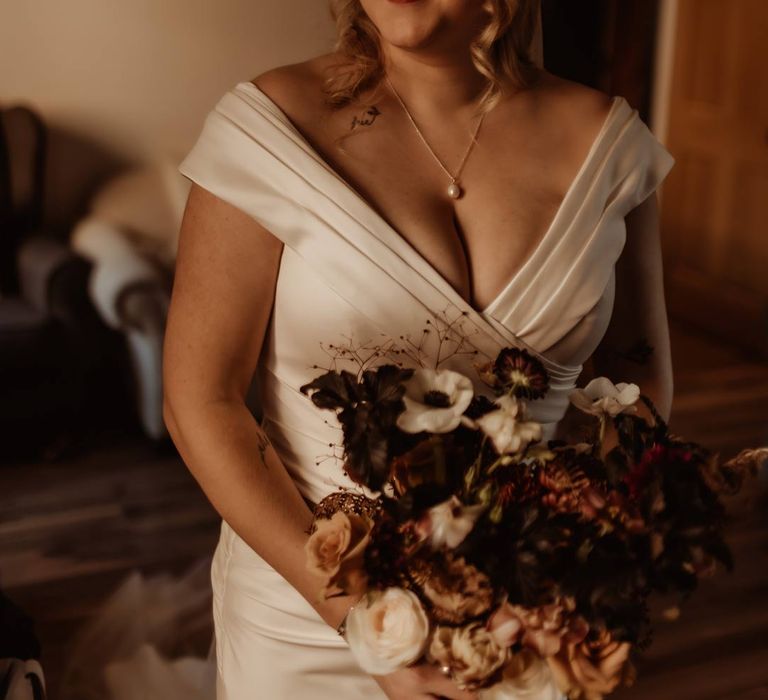 Bride in satin deep v wedding dress holding white, dusky pink and burnt red dried flower, rose and peony bridal bouquet 