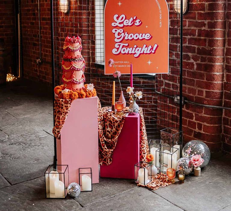 Retro wedding inspiration - large orange and pink retro wedding sign, retro wedding cake, leopard print wedding drapes, pillar candles and disco ball wedding decor 