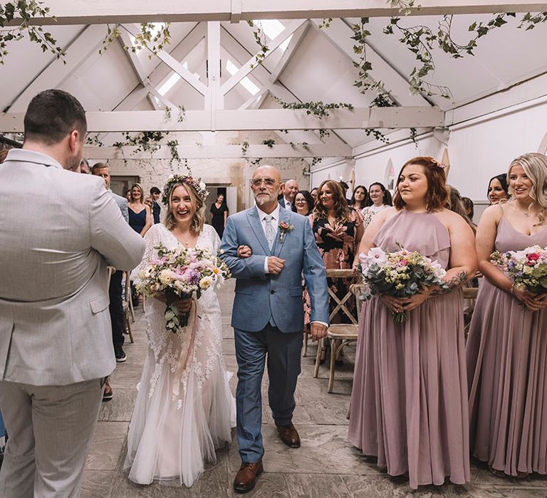 Bride walks down the aisle with the father of the bride to the groom waiting at the end 