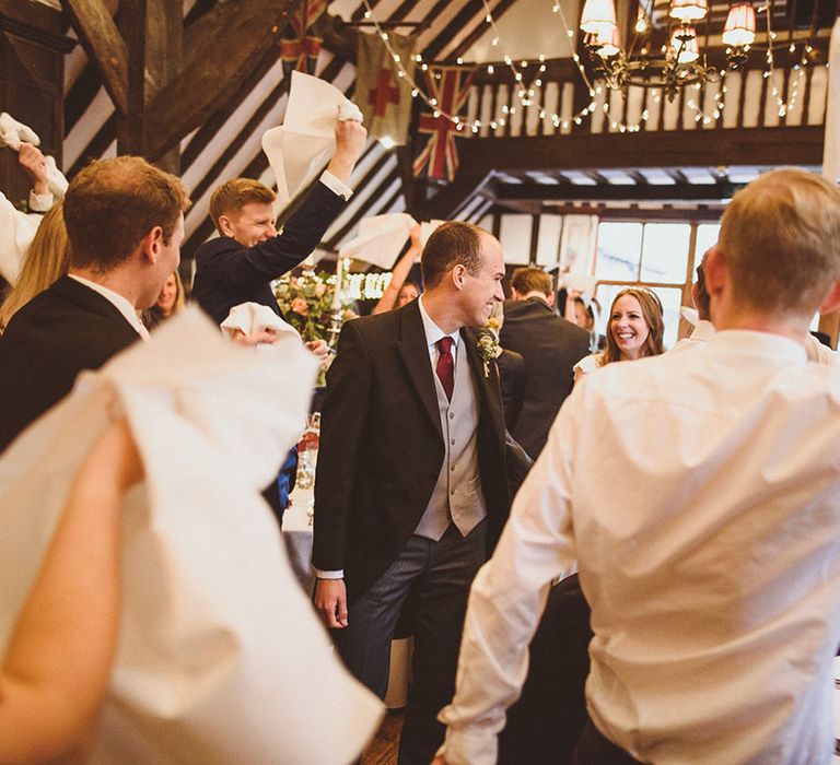 The wedding guests wave napkins in greeting to the bride and groom at the wedding reception 