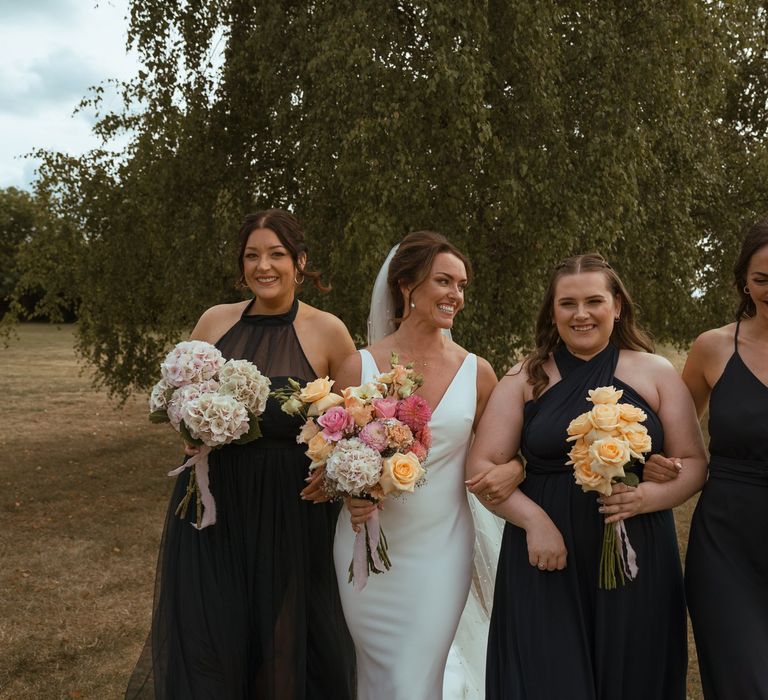 Bridesmaids in mismatched navy blue bridesmaid dresses by Rewritten Bridesmaids walking with the bride 