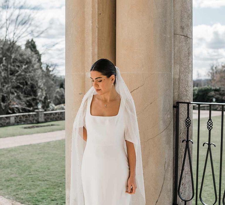 Bride in short sheer puff sleeve wedding dress with square neck and wrist loop at Buxted Park