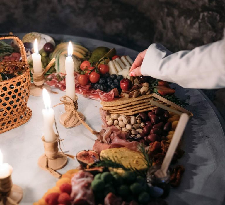 Bride taking a piece from wedding grazing table inside Margate Caves