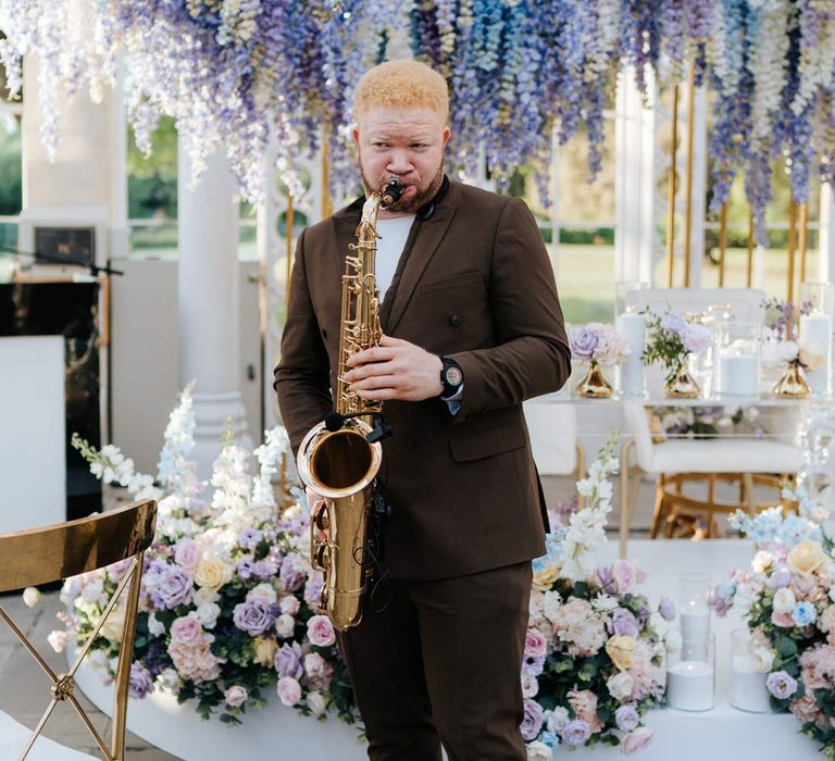 Live wedding saxophonist wearing brown suit and white trainers at Syon Park vow renewal ceremony