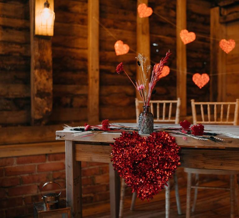 Glittery red heart wedding decor with black red and white pampas grass flower arrangement at Southlands Barn