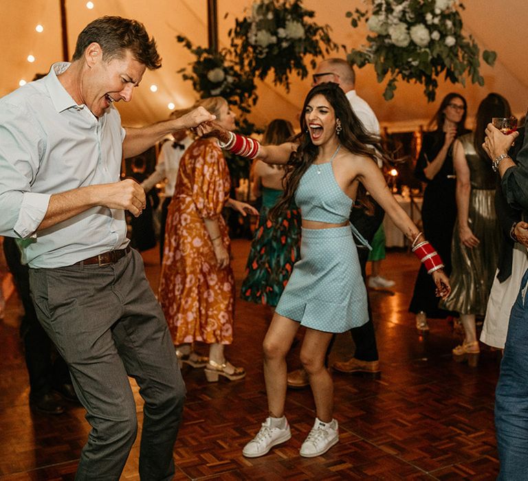 The bride in a blue colourful top and skirt two piece dancing with guests on the dance floor 