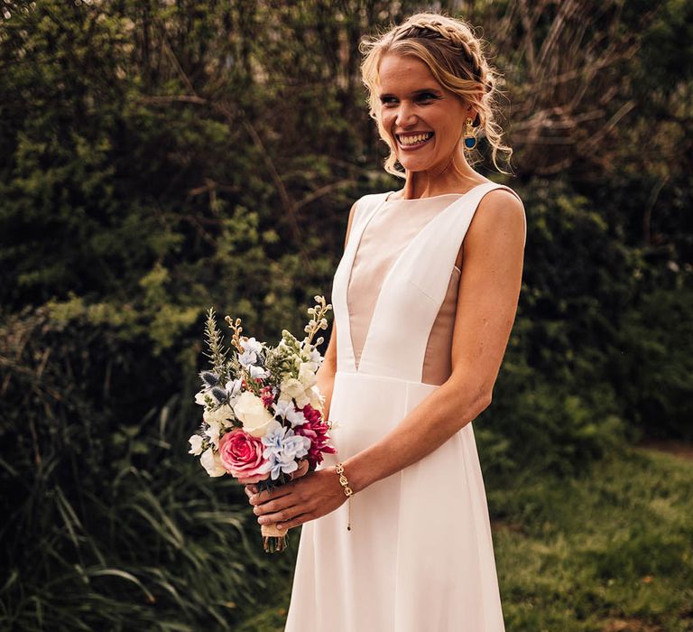 Bride in classic Andrea Hawkes Milo wedding dress with mesh insert holding colourful bouquet for spring church wedding 