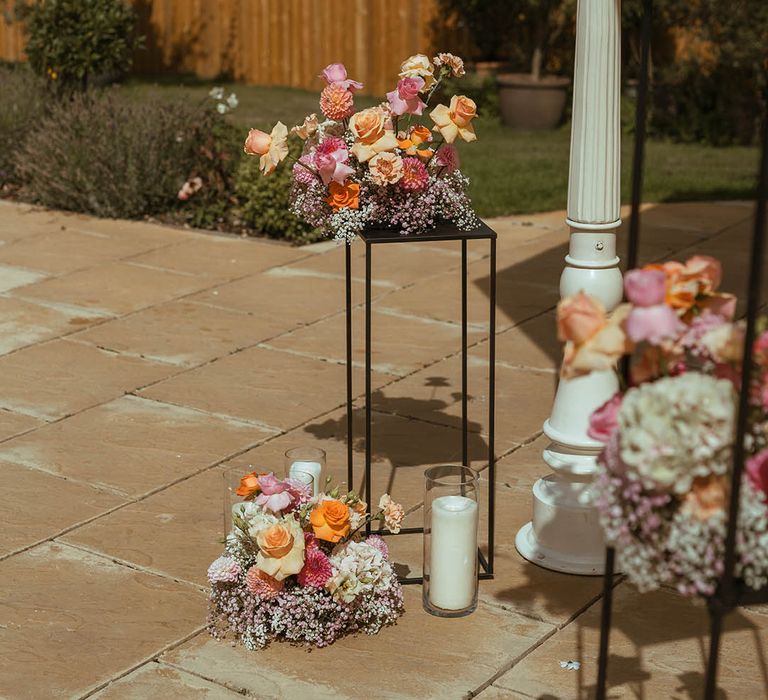 Orange and yellow wedding flower arrangements on black frames with gypsophila