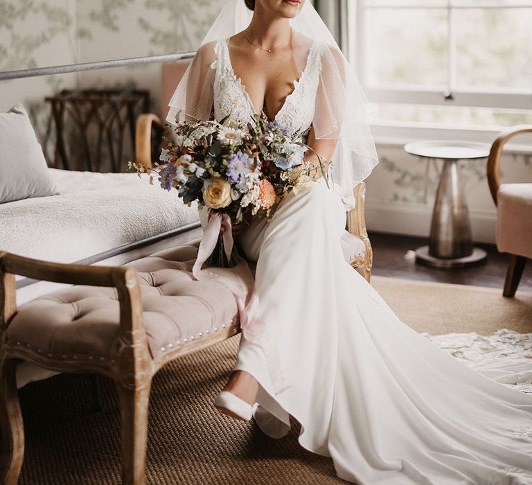 Bride in Justin Alexander wedding dress with the bride holding a pastel wedding bouquet and floral headband 