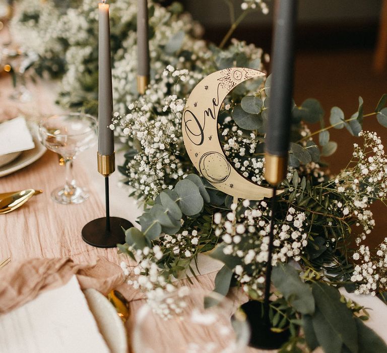 Crescent moon table name sign with white gypsophila table runner an black taper candles 