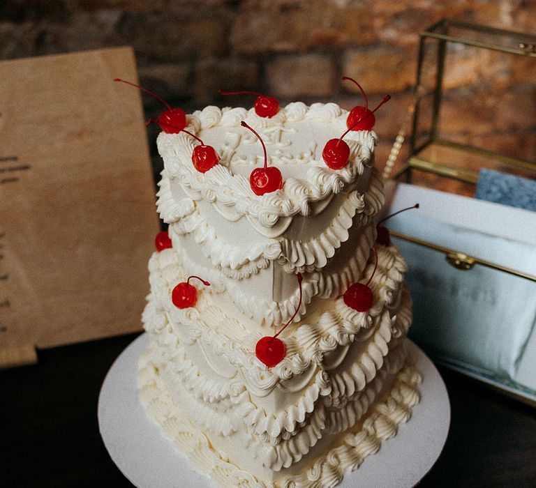 Heart shaped retro wedding cake decorated with white frosting and topped with cherries 