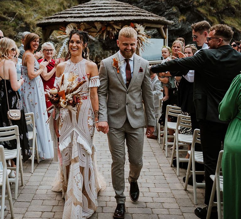 The bride and groom walk back down the aisle as a married couple together 