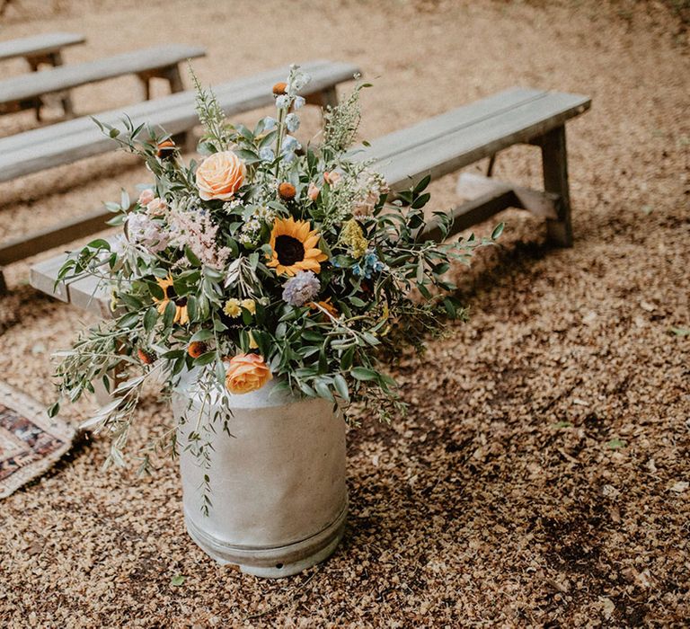 Milk churn filled with wedding flowers for aisle decoration 