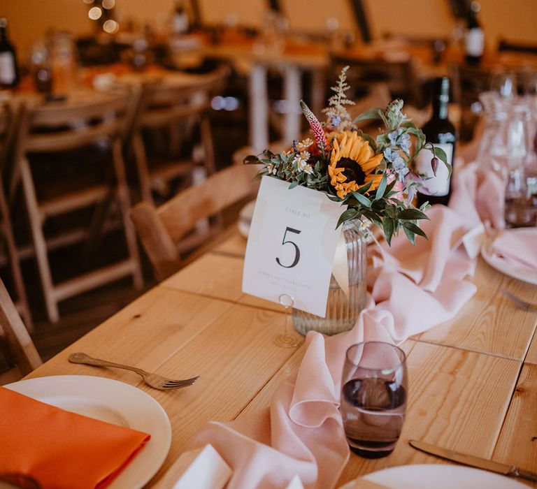 Banquet tables for tipi wedding with pink table runners and simple wedding table number signs 