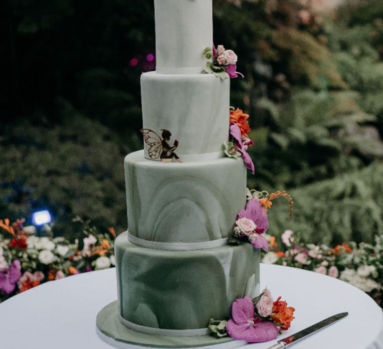 Green marbled four tier wedding cake with pink and purple flowers and gold fairy 