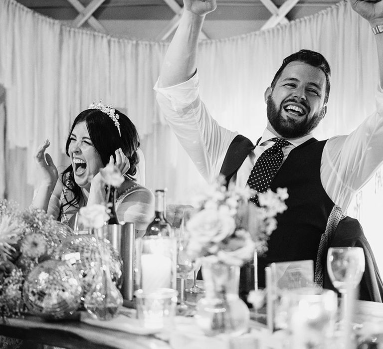 Bride and groom laugh together during wedding speech