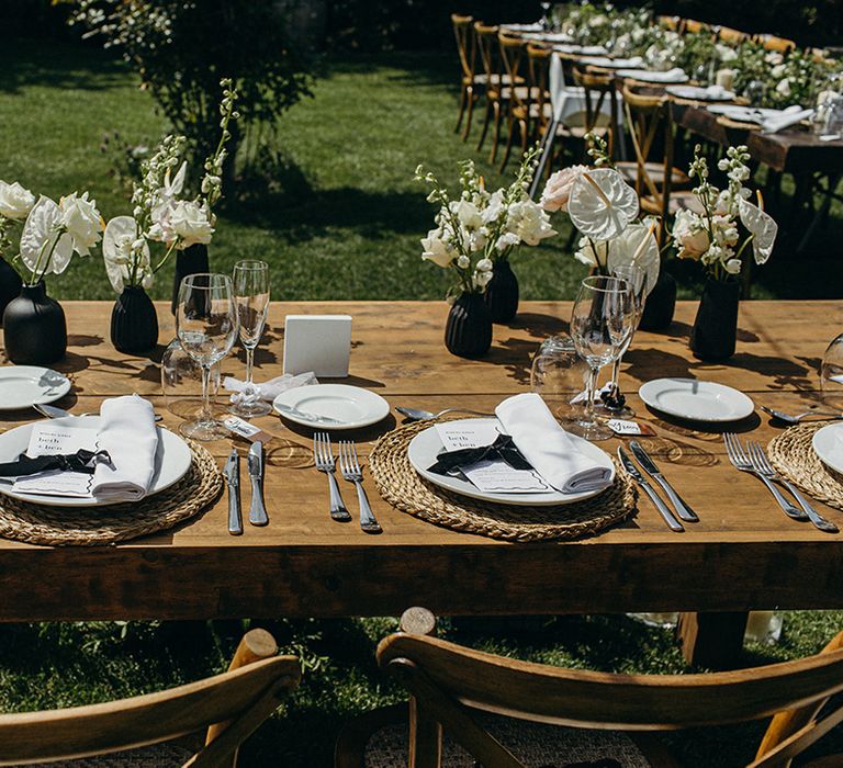 Wicker place mats with white plates and black bows for the table place setting 