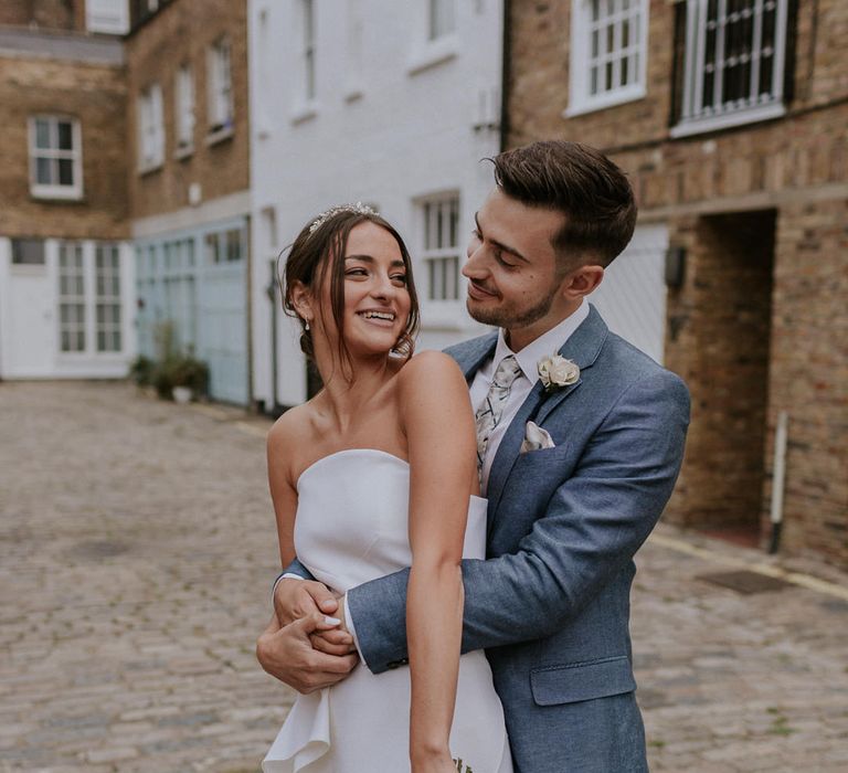 Groom in blue suit embracing his bride in Roland Mouret wedding dress