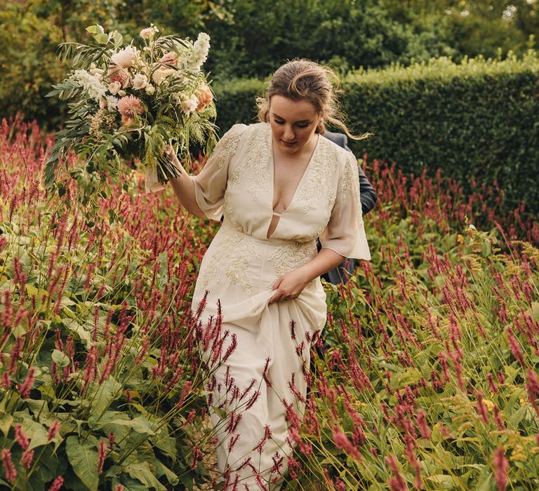 Bride in ivory wedding dress walking through the gardens at CS Lewis House in Oxford 