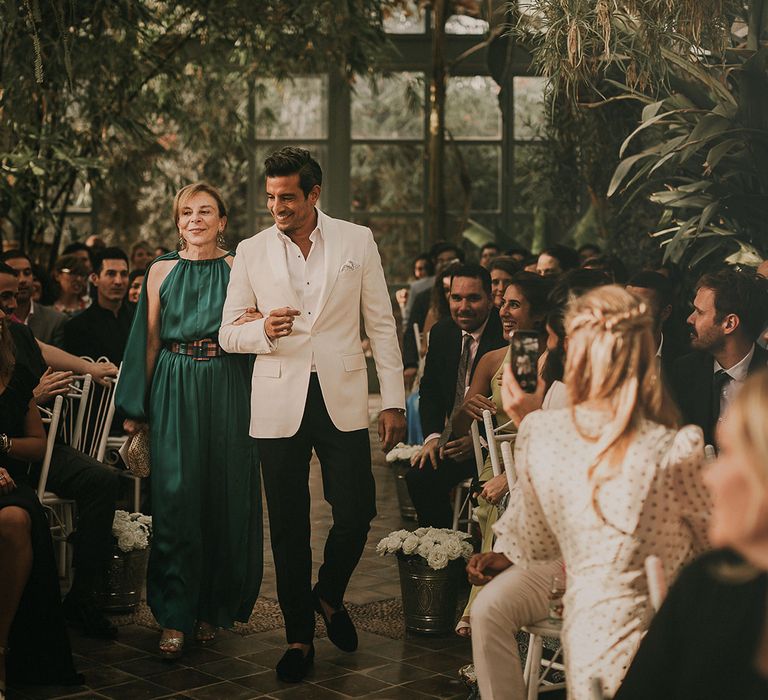 Groom walking down the aisle in a white dinner jacket 