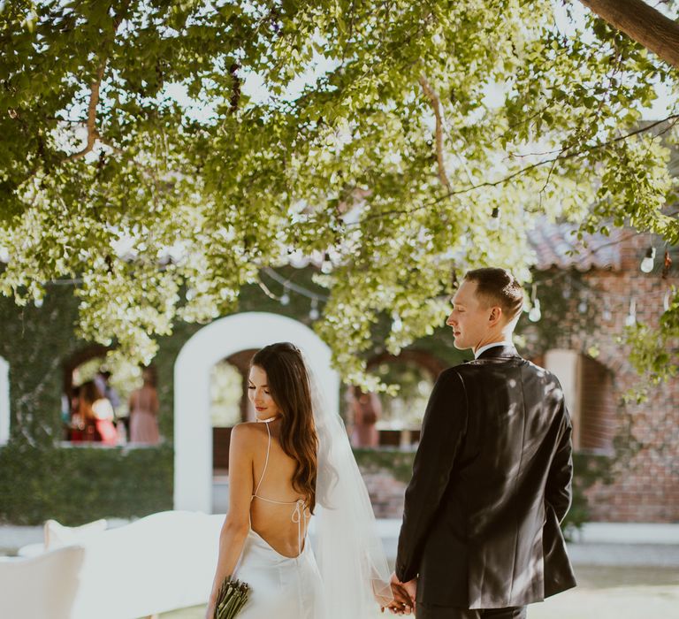 The bride and groom hold hands at out door wedding in Mexico