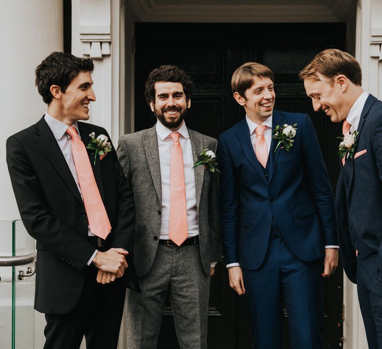 Groom stands and laughs with wedding party 