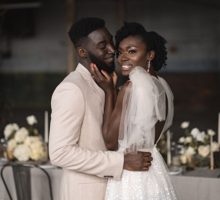 Bride in Berta wedding dress with bow shoulder detail holding her grooms face 