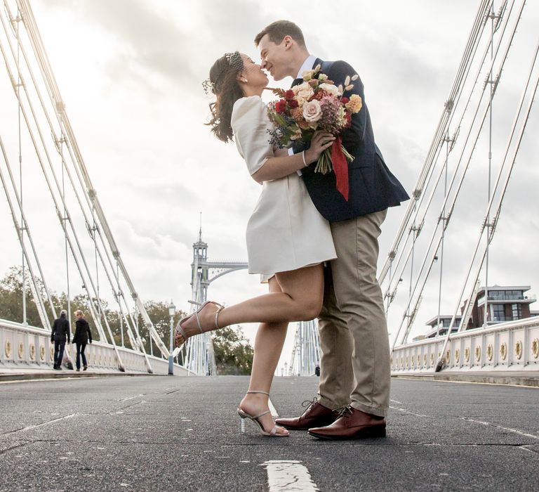 Bride in short wedding dress and Sophia Webster shoes flipping her leg up on a bride in London 