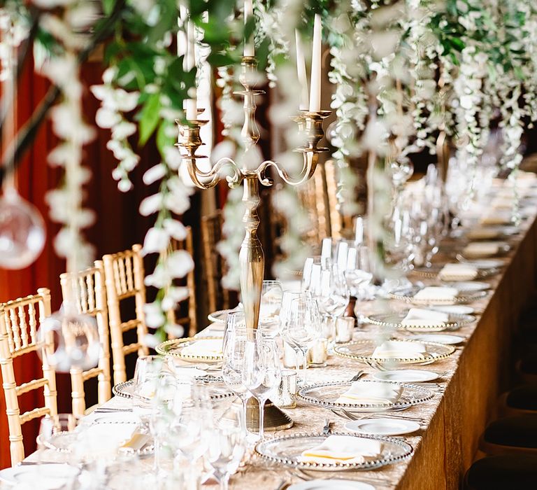 Luxury wedding reception at Leeds castle with glass charger plates, silver candelabras and flower installation