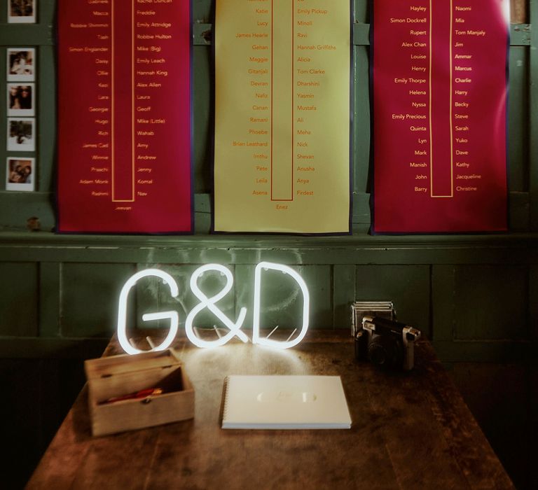 Red and yellow poster table plan and initial neon sign wedding decor 