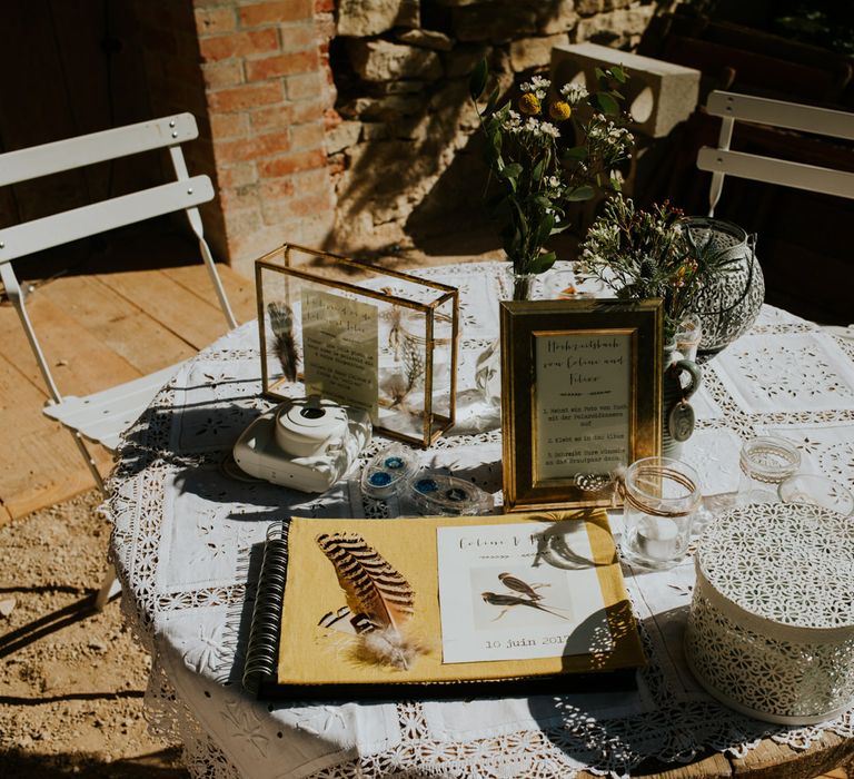 Lace table cloth with gold frame decor and wedding guestbook on