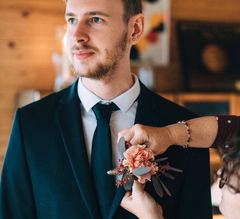 The groom having his pink carnation lapel flower fitted