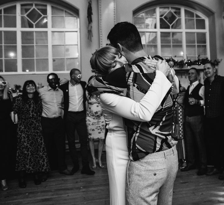 Black and white portrait of the bride and groom embracing on the dance floor 