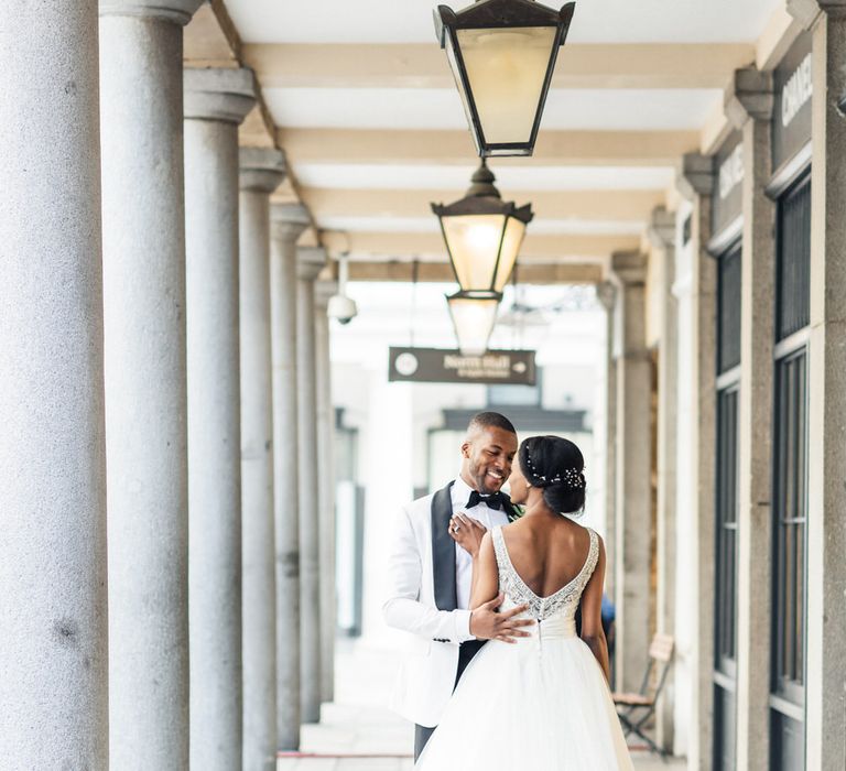 Bride walks beneath white pillars in London wearing tulle gown