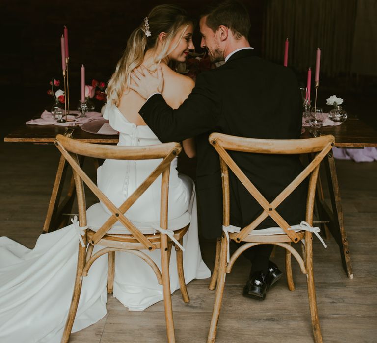 Bride & groom stare lovingly at one another in barn