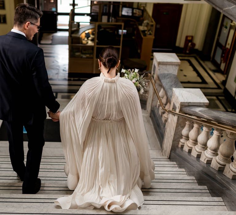 Bride in a floaty Lanvin wedding dress and bridal cape walking down the steps at Islington Town Hall