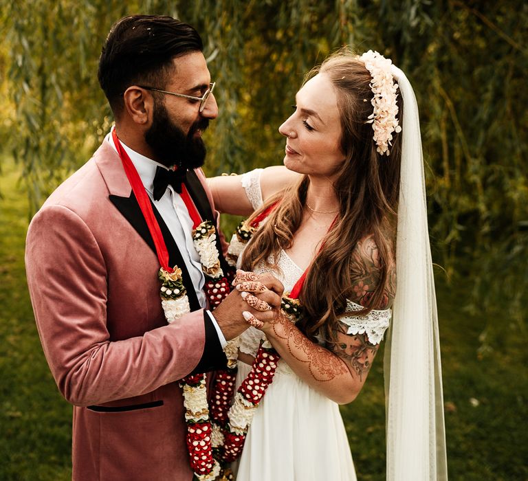 Bride & groom look lovingly at one another whilst stood outdoors in the garden