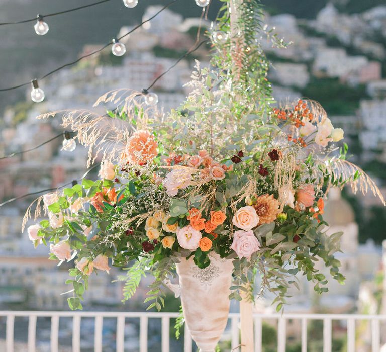 Large floral centrepiece with blush and terracotta flowers including roses and carnations, with wild grasses