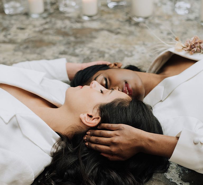 Brides lying on the industrial style floor for minimal all white wedding shoot