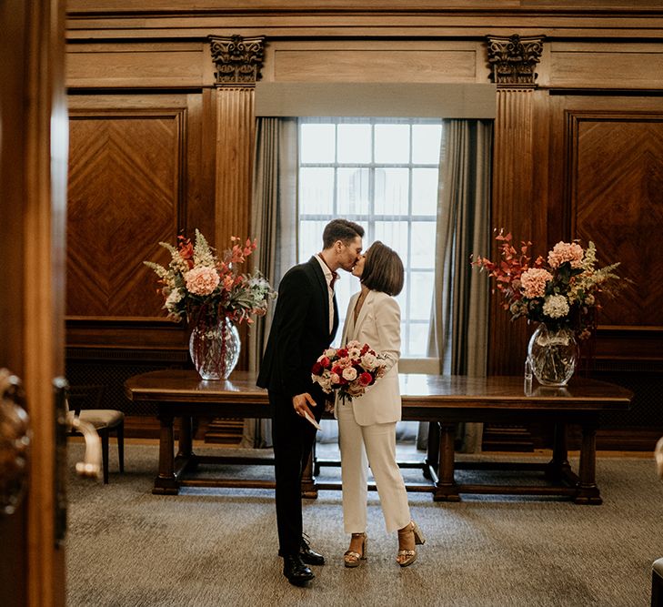 Bride & groom kiss in front of window during their wedding ceremony