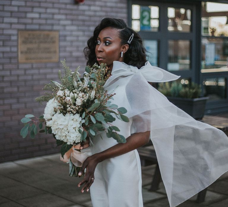 Bride in customised white Bec + Bridge wedding dress with shoulder bows, white and green wedding bouquet and curled wedding hair